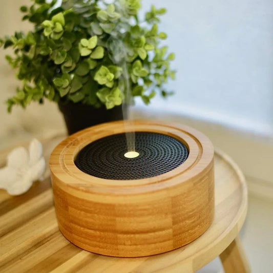 Bamboe aromadiffuser op houten tafel met stoom, groene plant en witte bloem op de achtergrond