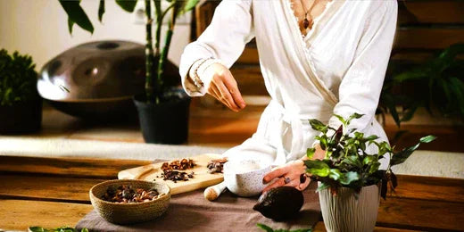 Persoon in witte outfit bereidt kruiden en cacaoboon op houten tafel voor wellness en natuurlijke gezondheid