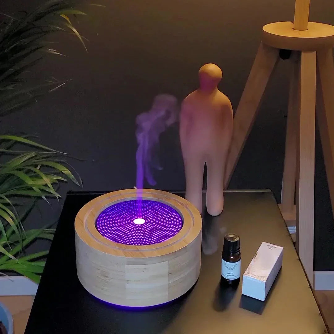 Houten aroma diffuser met paarse LED licht, geurstokje, olieflacon en decoratief beeld op zwarte tafel